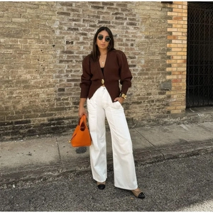 Minimalist V-neck knit cardigan with gold buttons paired with white wide-leg trousers