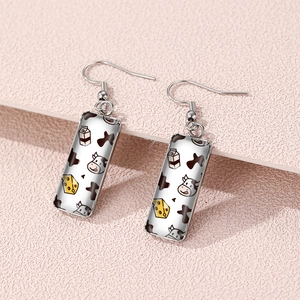 Detail of rectangular cow print earrings featuring cute cartoon milk and cheese illustrations