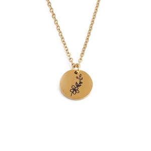 Detail shot of a round golden stainless steel pendant with floral engraving on white background