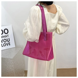 Detail of transparent fuchsia tote bag showing PVC material and woven shoulder strap