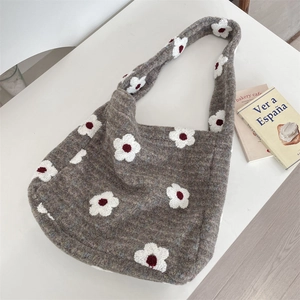 Macro detail of plush grey knit fabric with 3D white floral patterns on a tote bag