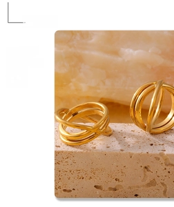 Detail of 18k gold plated stainless steel layered cross wrap ring on stone background