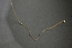 Macro detail of 14K gold plated silver chain featuring small beads and a heart charm