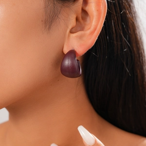 Detail of dark purple chunky C-shaped hoop earring in matte finish worn by a model