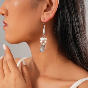 Detailed close-up of a silver drop earring featuring white pearls and a delicate metal leaf