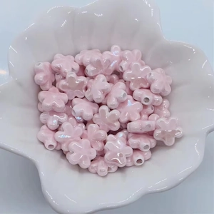 Macro di perline di ceramica rosa perlata a forma di fiore dentro una piccola ciotola bianca
