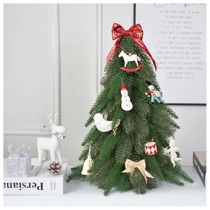 Close-up of a green mini table Christmas tree with snow effect and red ribbon ornaments