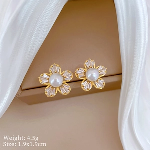 Detailed close-up of a five-petal gold flower earring with a pearl and zircon stones