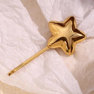 Detailed macro view of 18K gold plated stainless steel star hair clip on white paper