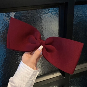 Detail view of a large burgundy satin bow hair clip with elegant double-layered fabric
