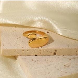 Close-up of golden irregular geometric ring on stone surface with satin background