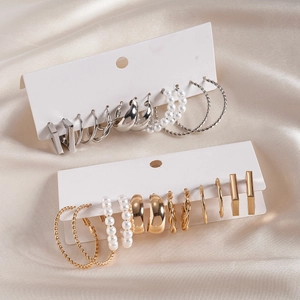 Twelve pairs of gold and silver geometric twist earrings with pearls on silk background