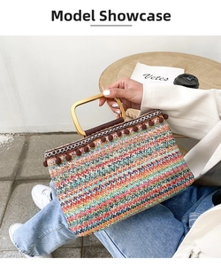 Detail of colorful woven straw handbag with pom pom trim and metal handle for summer