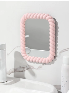 Pink twist-textured vanity mirror mounted on a gray marble wall over a sink
