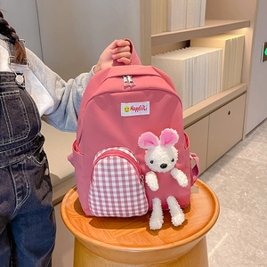 Pink cartoon kids backpack with red checkered pocket and plush rabbit charm