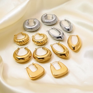 Minimalistische goud en zilver titanium stalen oorringen op zijden achtergrond