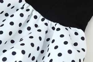 Detail close-up of monochrome polka dot dress with pleated waist and fabric texture