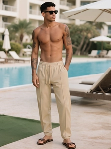 Dettaglio dei pantaloni beige da uomo con coulisse in vita e piega centrale dritta