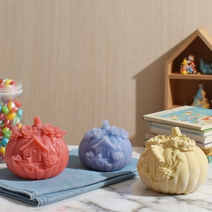 Detailed relief patterns on three colorful pumpkin-shaped candles on a marble table