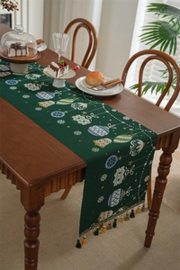 Detail of dark green Christmas table runner with festive bell and snowflake patterns