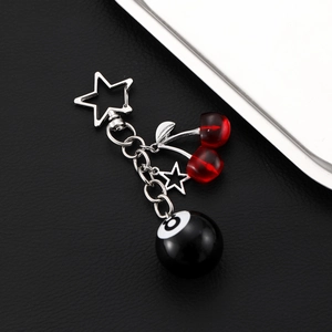 Detail of red cherry and number 8 billiard ball charms on a stylish metal keychain