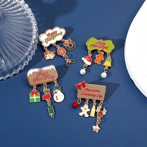 Detail of four colorful enamel Christmas brooches with hanging pendants and festive text