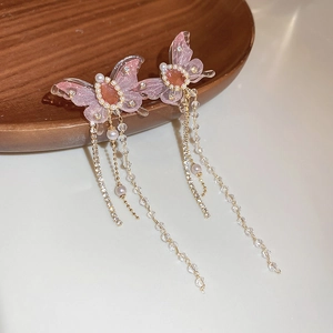Detail view of pink butterfly earrings with long tassels, rhinestones and pearls