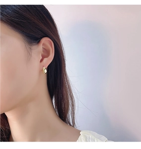 Close-up of minimalist gold teardrop sterling silver stud earrings worn by a model