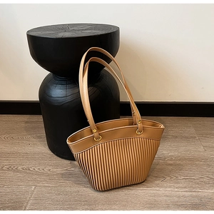 Detail of pleated khaki PU leather handbag texture with gold rings and slim straps