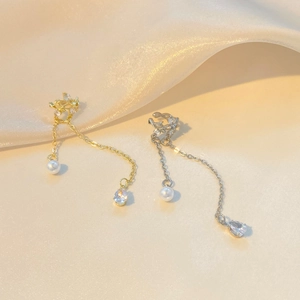 Detalle de ear cuffs de oro y plata con borlas de perlas y circonitas sobre seda