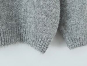 Detail of light gray knit sweater showing ribbed hem and soft wool texture fibers