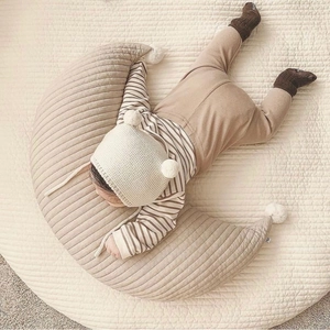 Detailed view of quilted cotton moon nursing pillow with pom-poms for newborn support