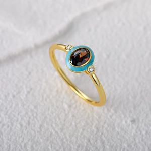 Detail of vintage gold ring with dark brown gem and light blue enamel inlay