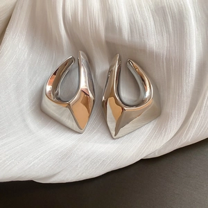 Vue macro de boucles d'oreilles géométriques argentées au design creux irrégulier