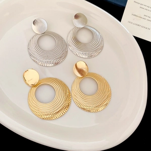 Gros plan de boucles d'oreilles rondes en métal doré et argenté avec textures radiales fines