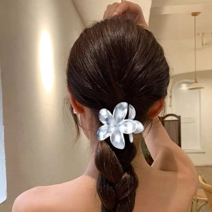 Elegant pearl white flower hair claw clip securing a low ponytail on a model from behind