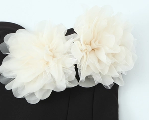 Dettaglio ravvicinato di fiori in mesh 3D color crema su un abito nero elegante