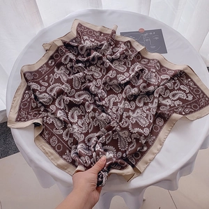 Brown paisley square silk scarf with beige borders displayed on a white round table