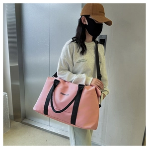 Detail shot of a large pink Oxford cloth travel bag worn by a model in a casual setting