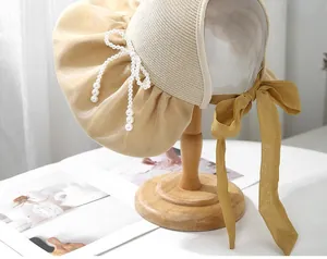 Detail of straw sun hat with champagne silk pleated brim and yellow ribbon bow