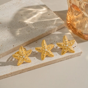 Detailed shot of gold starfish jewelry with crystal inlay on a textured stone base