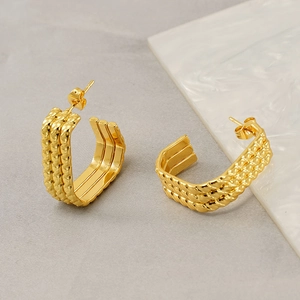 Golden multi-layer U-shaped stainless steel earrings with beaded texture on marble