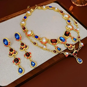 Close-up of vintage gold jewelry set with blue and red gemstones and white pearls