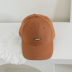 Minimalist brown cotton baseball cap for kids with white good embroidery on white desk