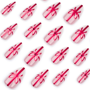 Faux ongles amande courts rose nude avec motifs nœuds rouges et strass brillants