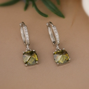 Detailed close-up of geometric hoop earrings with green square crystals and zircon pavé