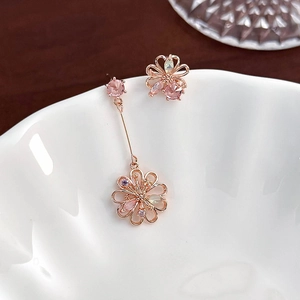 Close-up of asymmetric rose gold floral earrings with pink and purple crystals
