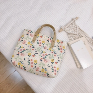 Close-up of floral canvas tote bag with leather handles and metal rivet details