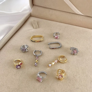 Close-up of assorted gold-plated geometric earrings with colorful zircons in a jewelry box