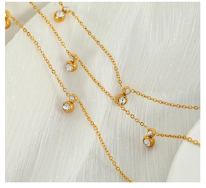 Macro detail of gold plated chain necklace featuring round bezel-set zircon pendants